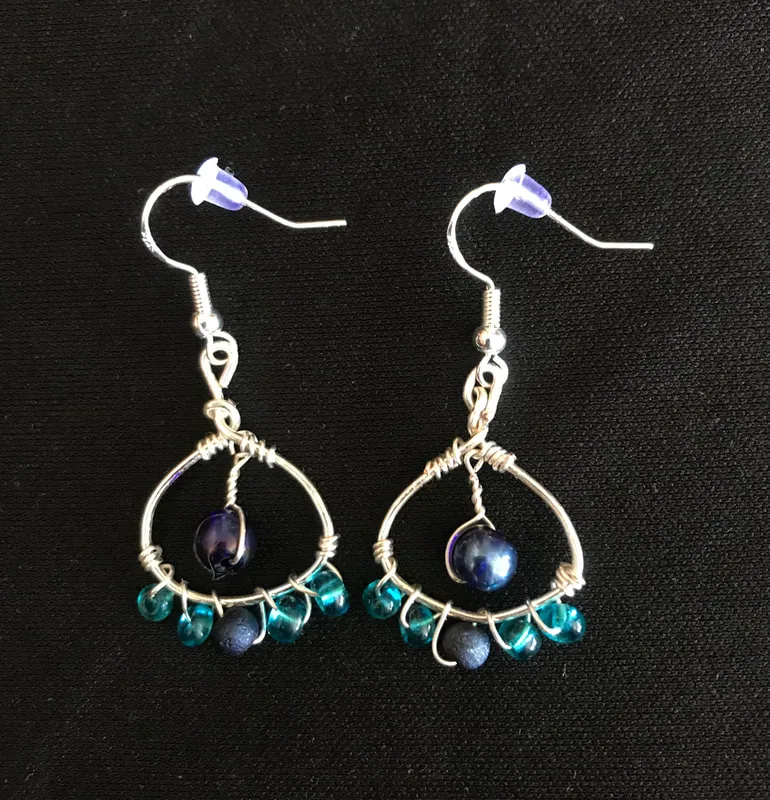 silver metal shaped earring with wirewrap and blue beads