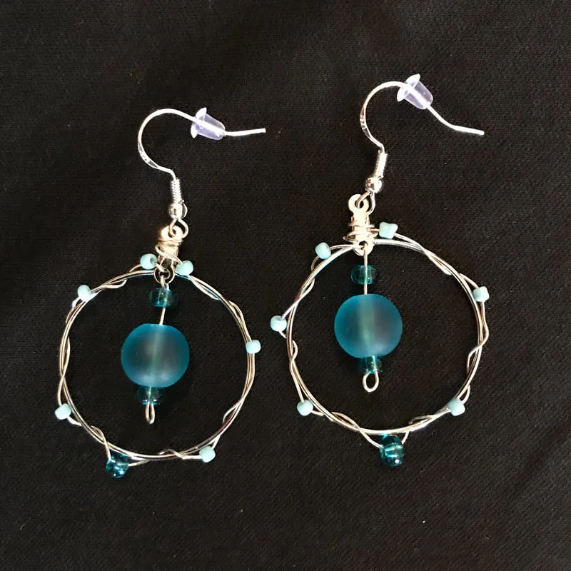 medium circle earrings a large blue bead in the center and smaller seeds beads wrapped around the earring